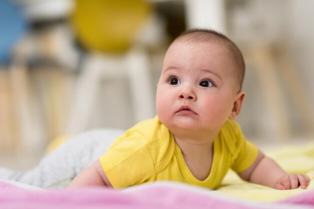 felice bellissimo neonato sdraiato su coperte colorate mentre gioca i primi giochi sul pavimento di casa