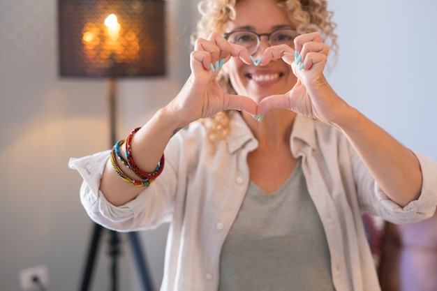 Felice bellissimo ritratto adulto di donna che fa a forma di cuore con le mani