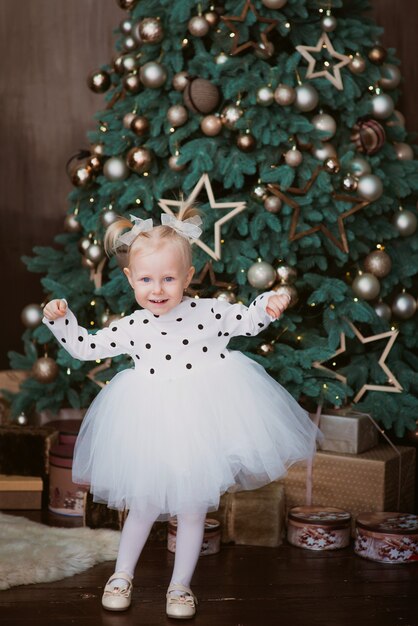 felice bimba bionda vicino all'albero di natale