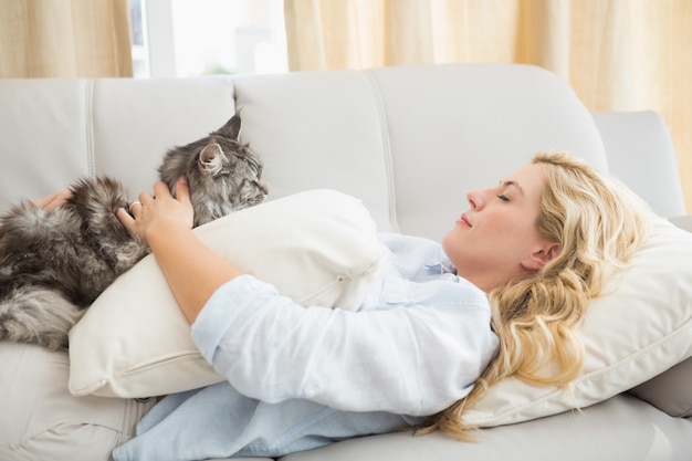 Felice bionda con gatto domestico sul divano