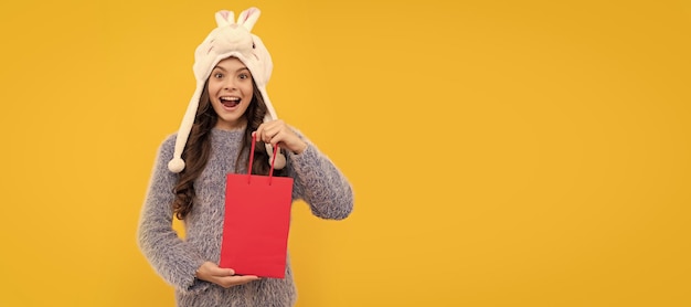 Felice capretto capelli lunghi in cappello tenere confezione su sfondo giallo anno nuovo Banner di shopping bambina studio poster intestazione con spazio di copia