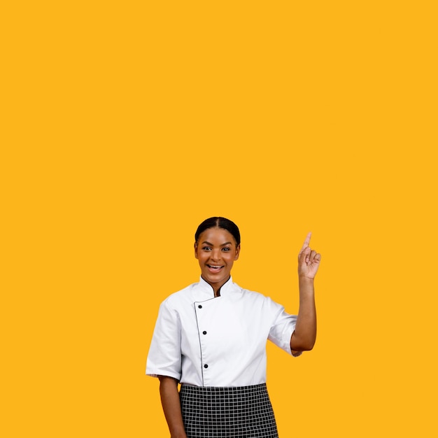 Felice chef femminile afroamericano che punta verso lo spazio della copia con il dito