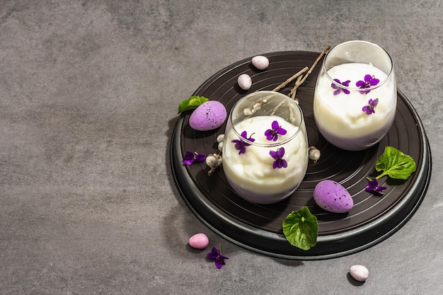 Felice composizione festiva di Pasqua Dessert di panna cotta vegano con fiore viola fresco