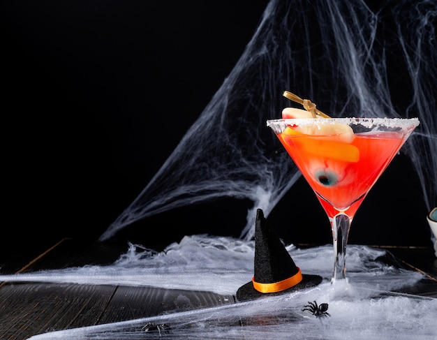 Felice concetto di Halloween. Cocktail di Halloween colorato e spaventoso con decorazioni per feste su sfondo scuro con ragnatela con spazio per le copie