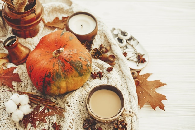 Felice concetto di ringraziamento Zucca caffè candela caduta foglie bacche noci ghiande cotone cannella su maglione e legno bianco rustico Saluti stagioni Accogliente immagine autunnale
