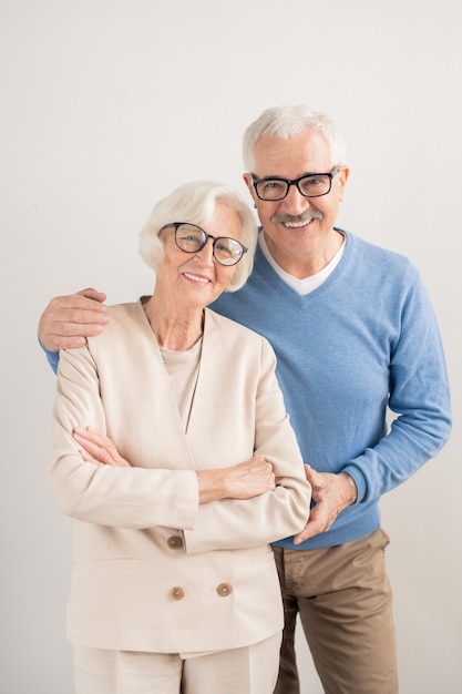 Felice coppia affettuosa senior con sorrisi a trentadue denti su muro bianco in piedi