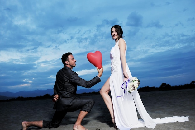 felice coppia appena sposata che festeggia e si diverte al bellissimo tramonto sulla spiaggia