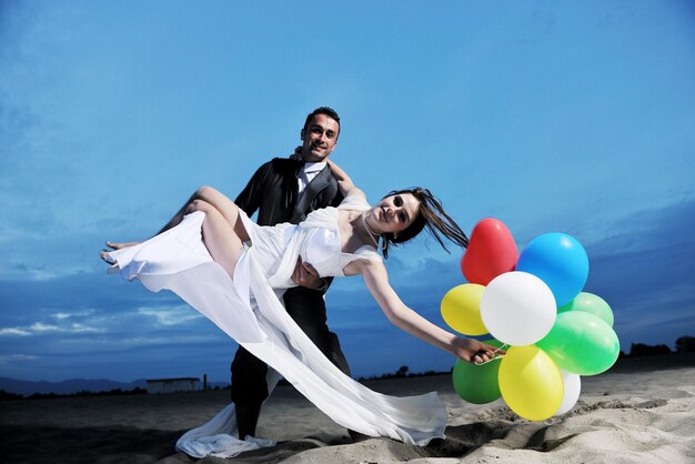 felice coppia appena sposata che festeggia e si diverte al bellissimo tramonto sulla spiaggia