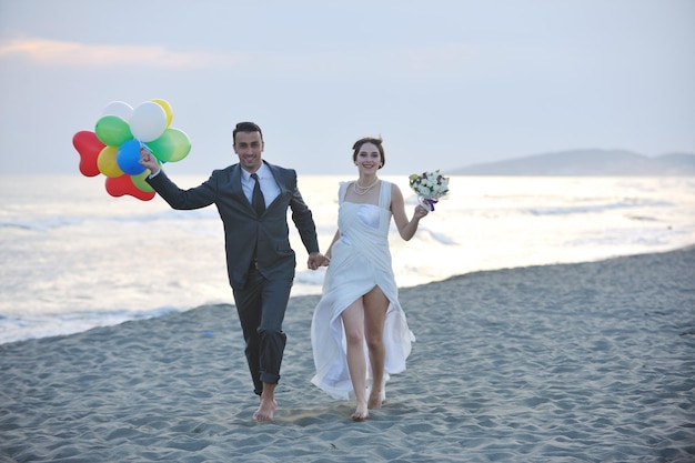 felice coppia appena sposata che festeggia e si diverte al bellissimo tramonto sulla spiaggia