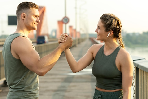 Felice coppia atletica che stringe la mano durante l'allenamento fitness sulla strada della città