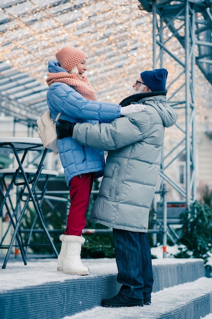 Felice coppia di anziani quasi abbracciati all'aperto in una giornata invernale. La sua mano tocca la sua spalla e la sua mano tocca la sua vita