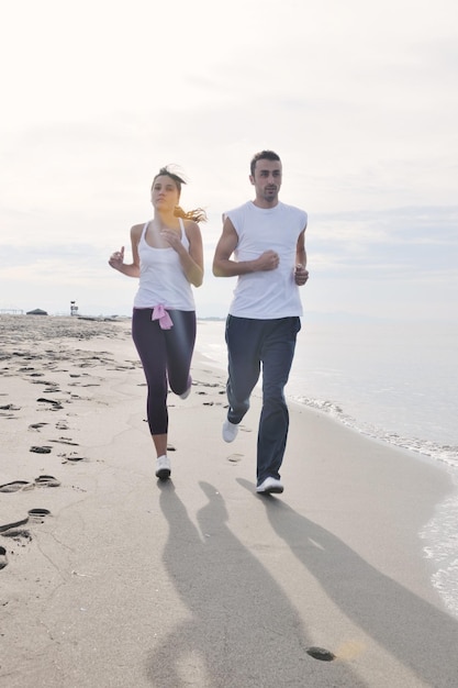 felice coppia giovane correre e fare jogging sulla spiaggia al mattino presto