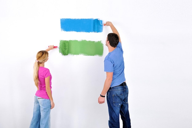 felice coppia giovane dipingere in colore verde e blu muro bianco della loro nuova casa