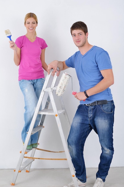 felice coppia giovane dipingere in colore verde e blu muro bianco della loro nuova casa