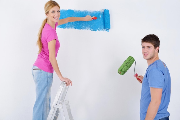 felice coppia giovane dipingere in colore verde e blu muro bianco della loro nuova casa