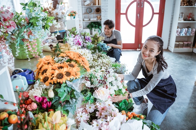 Felice coppia giovane indossando il grembiule controllo condizione fiore lavora nel negozio di fiori