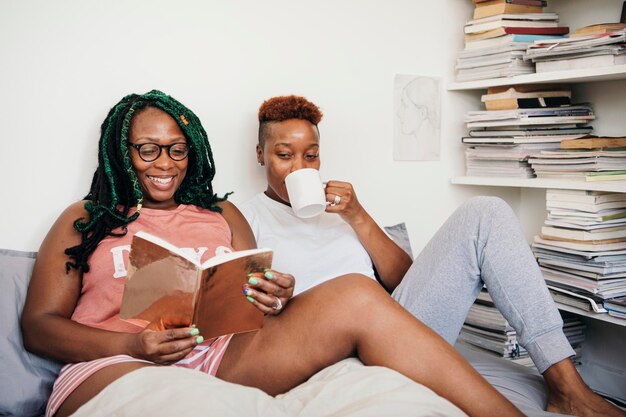 Felice coppia lesbica che legge un libro e beve caffè