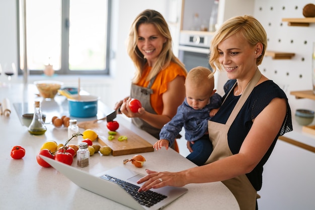 Felice coppia lesbica con bambino che prepara cibo a casa insieme. Cucina, cibo, divertimento, concetto di famiglia