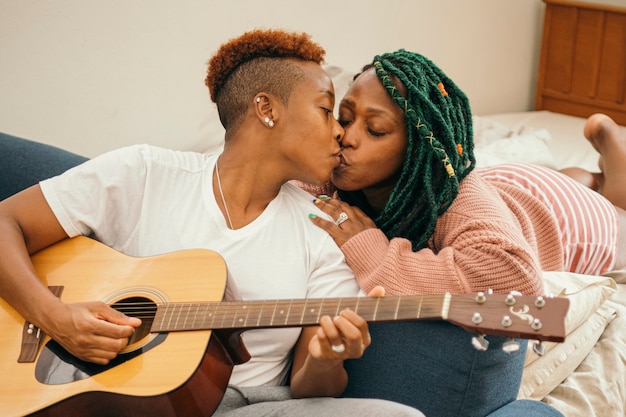 Felice coppia lesbica con un bacio alla chitarra