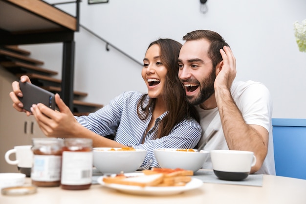 Felice coppia multietnica facendo colazione in cucina