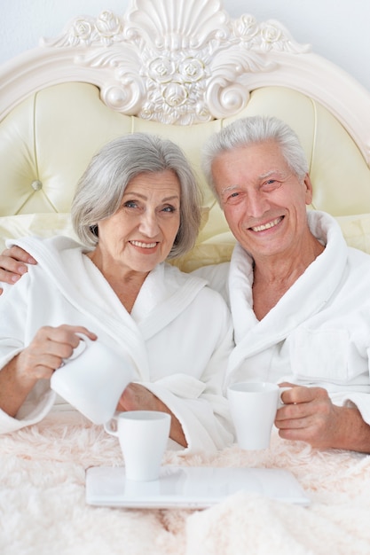 Felice coppia senior a letto con caffè