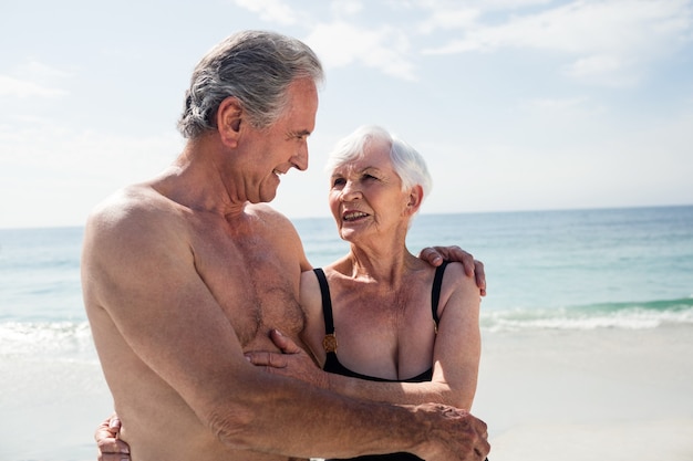 Felice coppia senior abbracciando sulla spiaggia