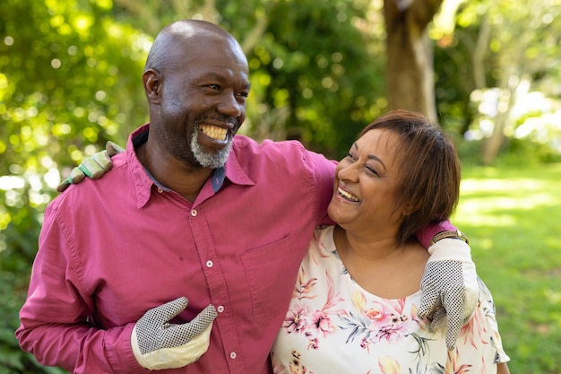 Felice coppia senior afroamericana con le braccia intorno al giardinaggio nel cortile