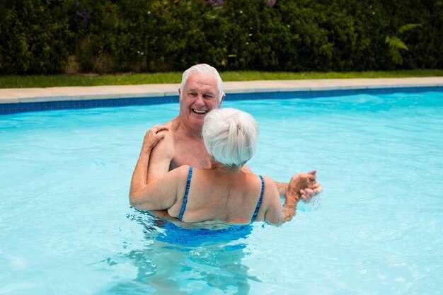 Felice coppia senior ballare in piscina