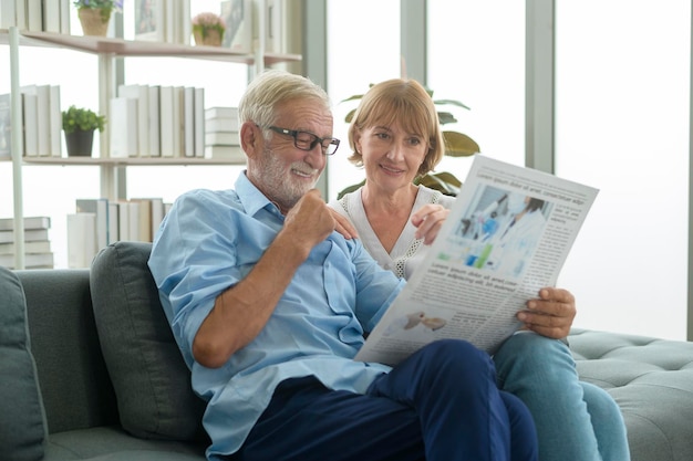 Felice coppia senior caucasica si rilassa, legge il giornale nel soggiorno