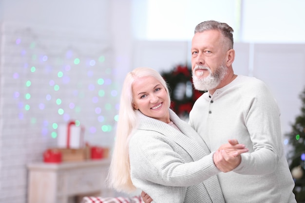 Felice coppia senior che balla a casa la vigilia di Natale Christmas