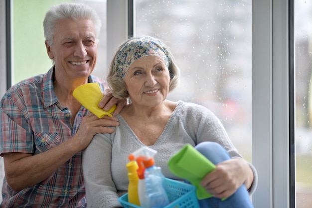 Felice coppia senior che pulisce la finestra a casa