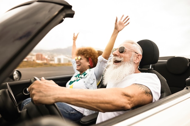 Felice coppia senior che si diverte in auto decappottabile durante le vacanze estive - Focus on man face