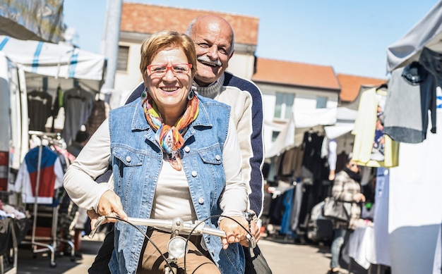 Felice coppia senior che si diverte in bicicletta al mercato cittadino