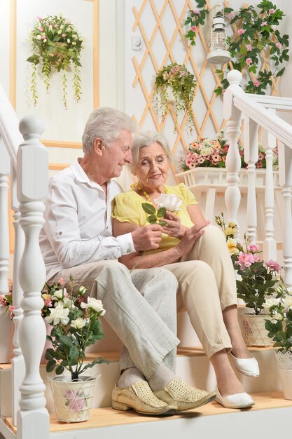 Felice coppia senior in posa a casa con i fiori