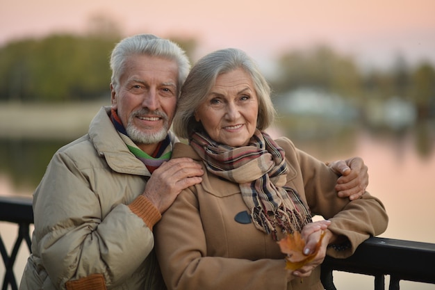 Felice coppia senior rilassarsi nel parco autunnale vicino al fiume