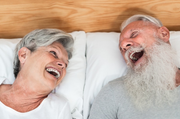 Felice coppia senior sposata divertirsi sdraiata a letto - Obiettivo principale sul volto di donna