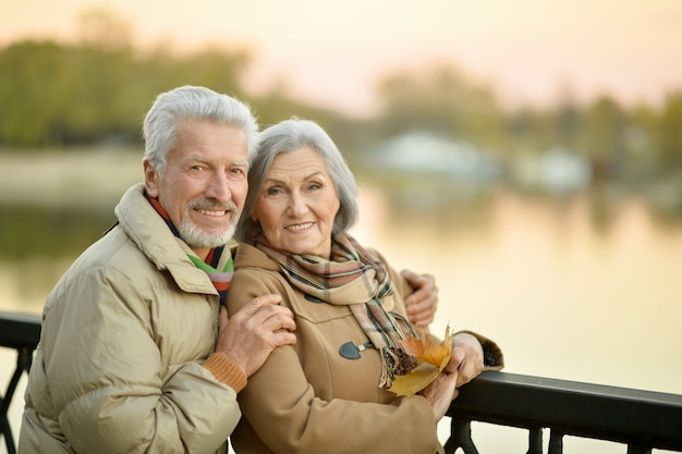 Felice coppia senior vicino al fiume in autunno, sfondo sfocato