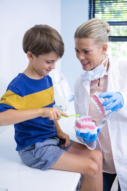 Felice dentista insegnamento ragazzo lavarsi i denti