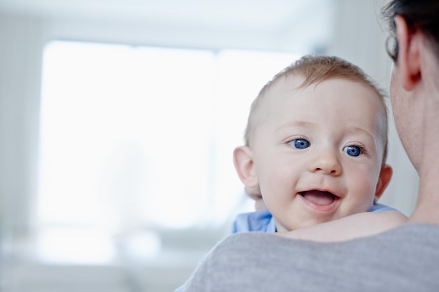 Felice di essere tra le braccia di sua madre Primo piano di un bambino felice che è trattenuto da sua madre