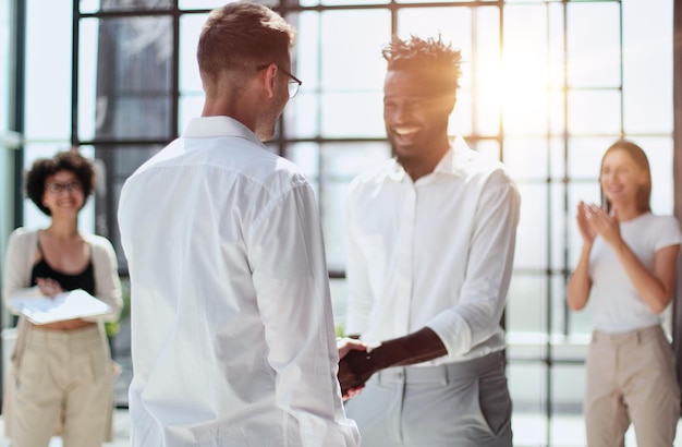 Felice di lavorare con te Giovani uomini moderni in abbigliamento casual elegante che stringono le mani e sorridono mentre lavorano nell'ufficio creativo