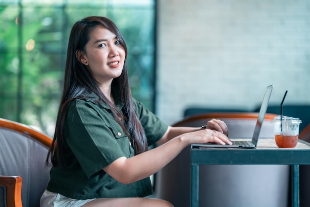 Felice di persone asiatiche freelance business femminile casual che lavora con un computer portatile con una tazza di caffè e smartphone nella caffetteria come il concetto di comunicazione in background