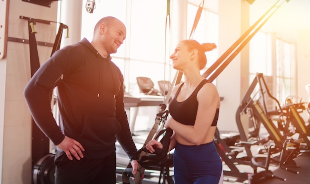 Felice donna adatta e uomo che parla durante una pausa dall'esercizio con cinghie di fitness