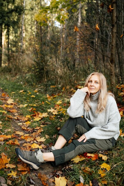 Felice donna adulta nella foresta di autunno