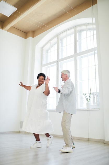 Felice donna africana che balla insieme a un uomo anziano durante la lezione di danza in studio