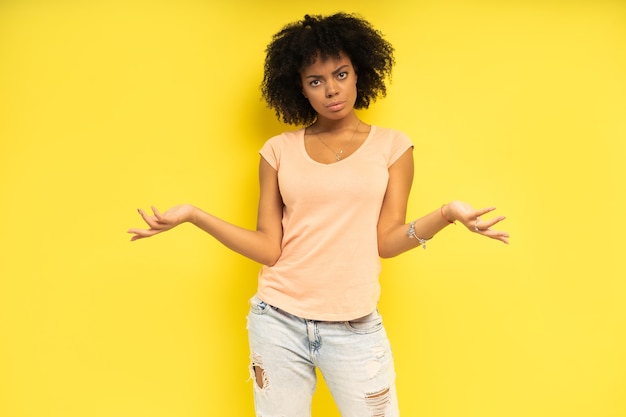 Felice donna afro-americana che sembra sorpresa su sfondo giallo.