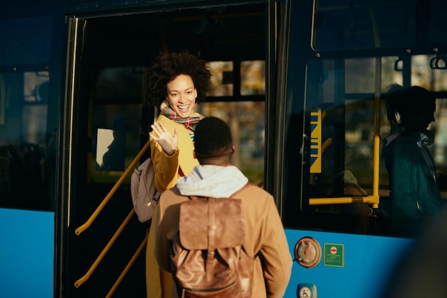 Felice donna afroamericana che saluta il suo ragazzo mentre sale su un autobus