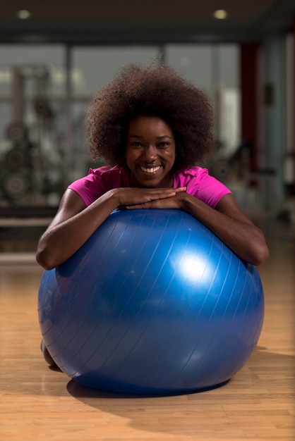 felice donna afroamericana con un'acconciatura afro riccia in una palestra rilassante dopo l'allenamento pilates