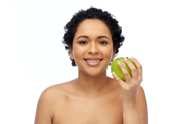 felice donna afroamericana con una mela verde in mano