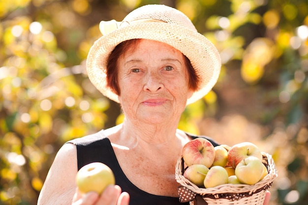 Felice donna anziana che tiene le mele all'aperto