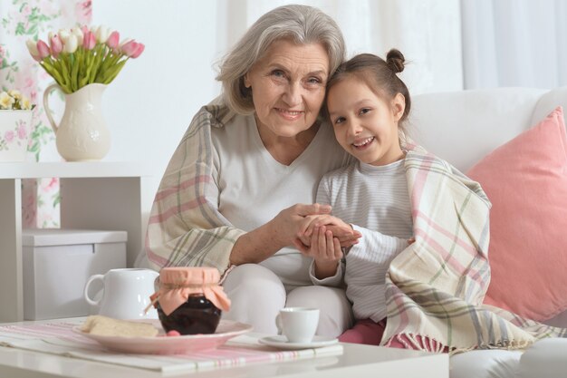 Felice donna anziana con nipote con tè a casa